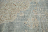 Distressed Oushak carpet with worn texture, highlighting pale blue and ivory floral motifs.