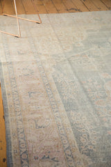 Distressed floral and arabesque patterns across pale blue field and ivory border.