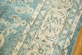 Distressed Oushak carpet close-up, faded blue-green and apricot palmette patterns with even wear.