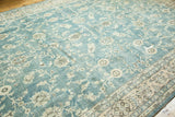 Distressed Oushak carpet corner with faded ocean blue-green field and ornate ivory-brown floral border.