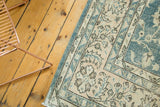 Distressed vintage Oushak rug corner with faded blue-green, apricot palmette motifs, even wear.
