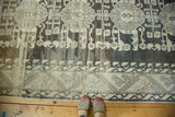 Distressed vintage Kula carpet end section with geometric patterns and strong charcoal-beige abrashes.