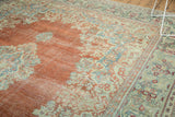 Distressed vintage Arak carpet detail with rust field, light blue floral motifs, and visible wear.