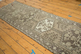 Oversize medallion with blossomed vinery on vintage Persian runner's charcoal and ivory pile.