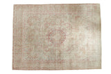 Distressed vintage Persian carpet with a raspberry red medallion on a sand-colored millefleur field.