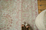 Close view of a vintage distressed carpet's wear and intricate raspberry millefleur pattern.