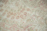 Worn texture of a vintage carpet showing the foundation grid beneath a raspberry floral design.