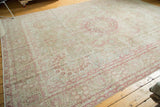 Angled view of a distressed Persian carpet showcasing its soft, faded raspberry and beige millefleur design.