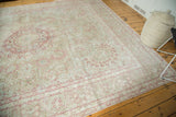 Angled perspective on the distressed vintage rug's soft, low pile and faded floral design.