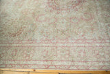 Worn texture of a vintage carpet reveals the foundation amidst raspberry and beige millefleur design.