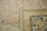 Distressed vintage Persian rug's ivory and blush pile with exposed foundation, revealing hand-knotted blue border.