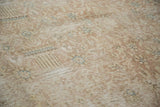 Distressed vintage carpet texture revealing localized foundation through faded blush and blue pattern.