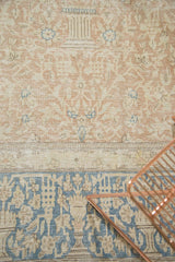 Distressed vintage hand-knotted Persian carpet showing faded dusty blush field and bold blue border pattern.