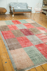 Evenly worn, distressed multi-paneled modern Oushak rug in faded reds, beige, and ocean green.
