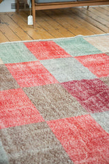 Distressed multi-paneled Oushak rug in cherry red, ocean green, silver, and sand tones.