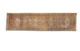 Distressed Serab runner rug with geometric medallions in blush peach, antique ivory, and dark brown.