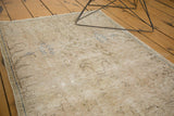 Distressed texture of vintage Persian rug, with exposed foundation and faded floral designs.