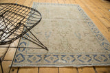 Vintage distressed Persian rug with worn beige pile, denim blue geometric border, and fringe.