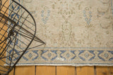 Distressed vintage Persian rug's blue geometric border, worn beige pile, and fringe detail.