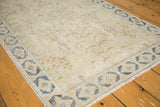 Distressed vintage rug corner with faded denim blue border and soft fringe.