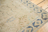 Distressed vintage rug's textured pile, showing worn beige, coffee brown, and blue floral motifs.