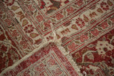Distressed corner of vintage Tabriz rug, revealing red and ivory patterns with visible foundation.