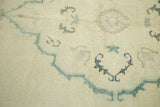 Close-up of vintage Oushak rug, showing time-softened cream pile and dusty green cloud band.