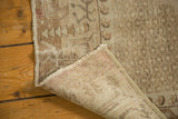 Corner of distressed Oushak rug revealing worn beige pile and tightly hand-knotted foundation.