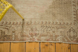 Distressed vintage Oushak rug detail showing faded beige pile and worn border pattern.