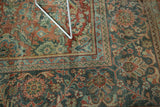 Distressed vintage Mahal carpet corner, showing terra cotta field and teal border with floral motifs.