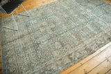 Distressed Tabriz carpet corner showing worn floral motifs in blue, ivory, and brown.