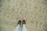 Faded Herati motif and distressed pile of a vintage Tabriz rug in ivory, sand, and blue.