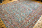 Distressed Persian Meshed carpet corner showing intricate scrolling tendrils and sky blue, red tones.