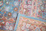 Distressed texture of sky blue and pomegranate red pile with ornate tendril motifs and blue fringe.