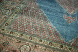 Distressed Mahal carpet corner: blush floral spandrel, pistachio green border, and stepped aqua field.