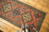 Pale terra cotta field of a vintage Heriz runner with geometric medallions and even wear.