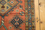 Heriz runner side border with terra cotta field, geometric blue motifs, and even pile texture.