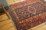 Cherry red geometric border with a hand-knotted navy blue field and ivory fringe.