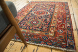 Vintage Karaja rug corner, showcasing light fringe, cherry red geometric border, and navy field.