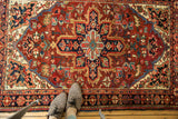 Traditional Heriz rug with geometric and curvilinear motifs in brick red and navy.