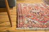 Hand knotted pile and traditional Heriz patterns in brick red, navy, and ivory, with fringed edge.