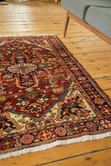 Hand-knotted Heriz rug's ivory fringe and brick red, navy, and beige traditional border.