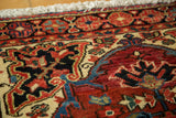 Detail of vintage Heriz rug: hand-knotted brick red, beige, navy curvilinear geometric pattern.