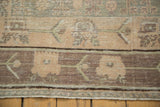 Distressed Khotan carpet's geometric vinery in oxidized silver, pale blush, and ivory.