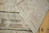 Distressed pile texture with pale silver and blush tones, revealing the hand-knotted rug foundation.