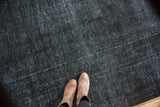 Distressed overdyed Sivas carpet's worn texture, showing charcoal and faint indigo colors.