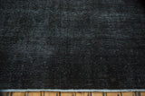Distressed Sivas carpet detail: charcoal black fine weave, even wear, secured edge.