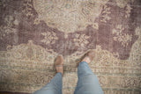 Distressed plum and beige floral field of a Sivas rug, with visible foundation.