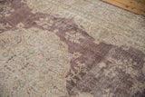 Detail of distressed Sivas carpet, showing plum and beige floral motifs with visible foundation.