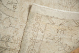 Close-up of distressed ivory pile, secured edge, and hand-knotted foundation of vintage Sparta carpet.